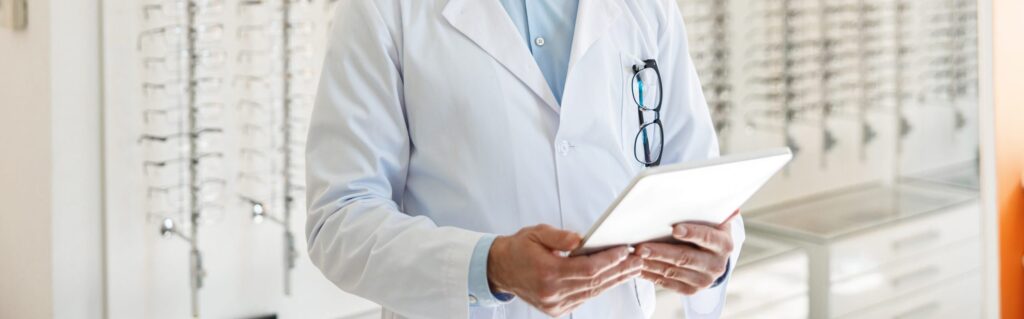 Ofaltamologista de óculos pendurado no bolso mexendo no tablet